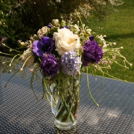 Arrangement de fleurs coupées dans un vase transparent avec Lysianthus, jacinthes, ail, anémones et roses «David Austin». 